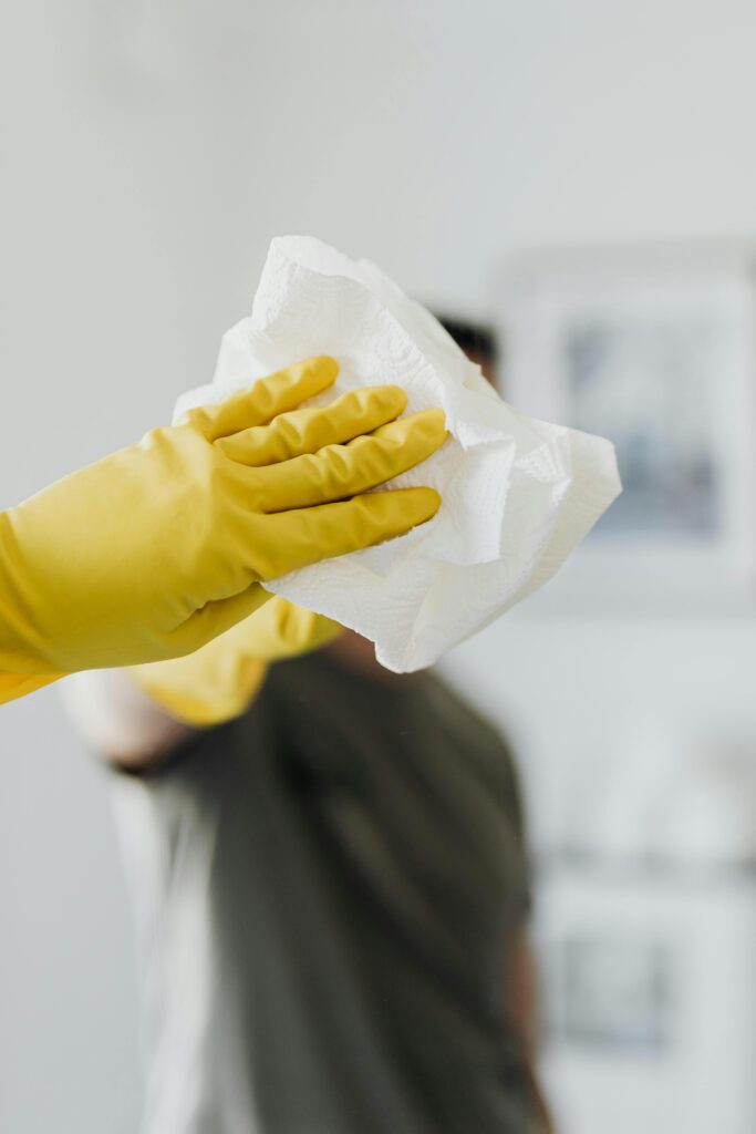 pexels photo 4239124 4239124 Anonymous male wearing yellow latex gloves and dark t shirt wiping mirror in bathroom with paper napkin